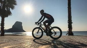 Cyclist cycling in Calpe in front of the sea and Penan Ifach rock