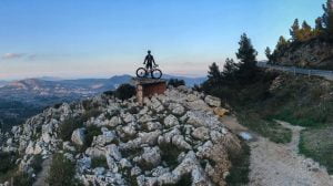 Cyclist near top of Coll de Rates with far-reaching view at dusk