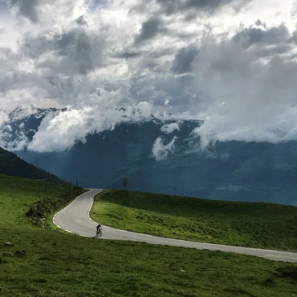 Cyclist on open road near top of Hautacam with thick cloud above