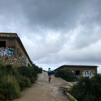 Cycling through abandoned buildings on the way up Talaia d'Albercutx climb Mallorca