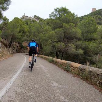 Cyclist climbing through woodland on the climb up Puig de Sant Salvador Mallorca