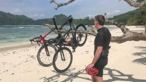 Cyclist after cycling in the Seychelles, standing on a beach