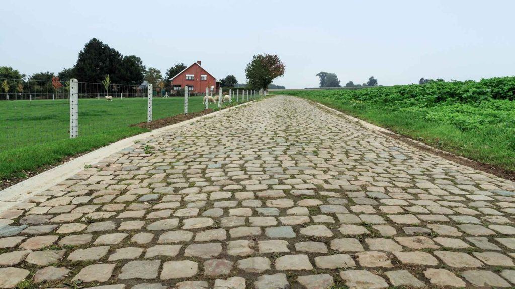 Small empty cobblestone street in a rural agricultural scene perfect for cyclists cycling Flanders, Belgium