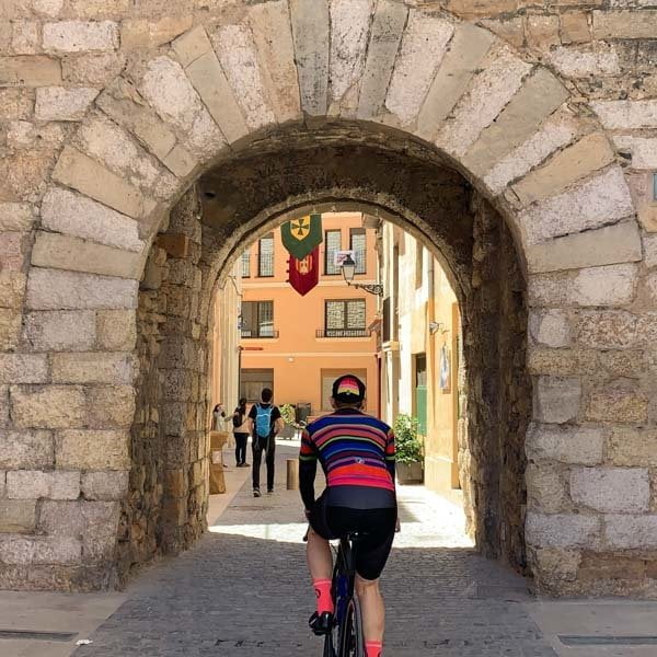 Cyclist cycling through medieval arch into Montblanc, costa daurada