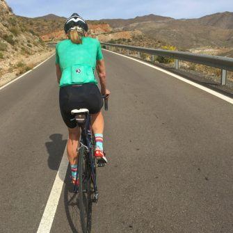 Cyclist in green jersey cycling on quiet road, Almeria