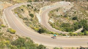 Cycling Andalucia with cyclist on long snaking road through Almeria