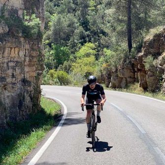 Cyclist beside craggy cliff wall, costa daurada