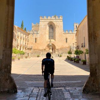 Cyclist entering Santa Creus monastery building complex