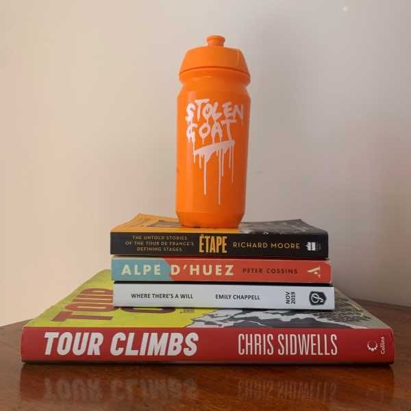 Pile of the best cycling books with stolen goat bottle on top