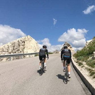 Two cyclists climbing from Passo Falzarego to Passo Valparello