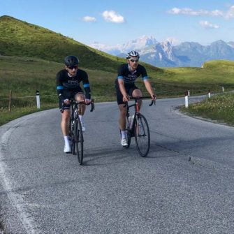 Two cyclists on Passo Giau, Dolomites with mountain backdrop