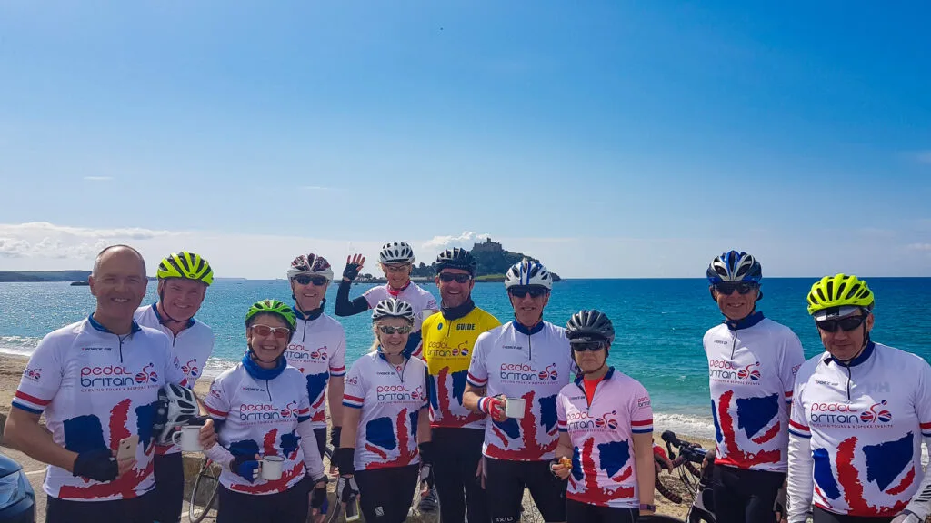 A group of cyclists on a LEJOG cycling challenge take a group photo infront of St Michael's Mount