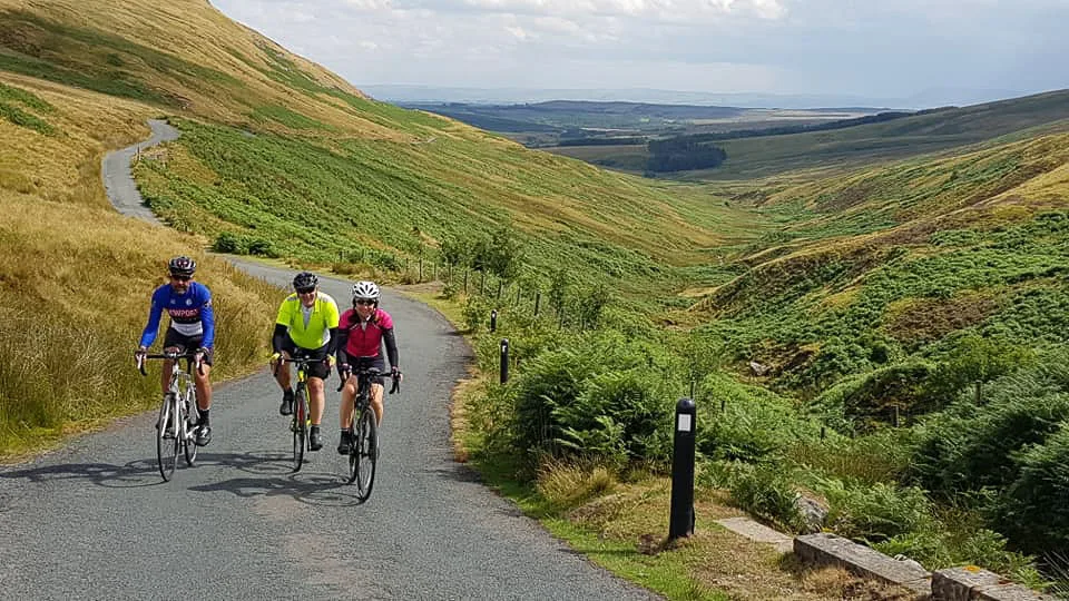 Three cyclists tackling "The Cross of Gree" in the Forest of Bowland