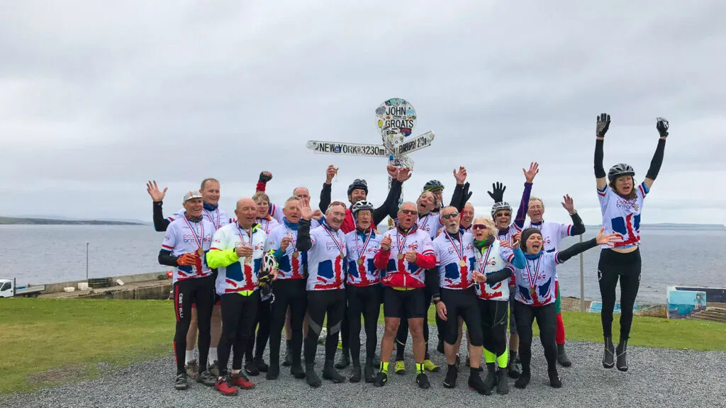 A group of cyclists celebrate completing the LEJOG cycling challenge