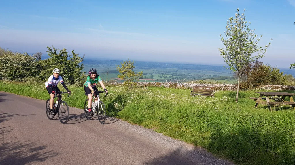 Two cyclists with beautiful views of the Mendip Hills in the distance on LEJOG