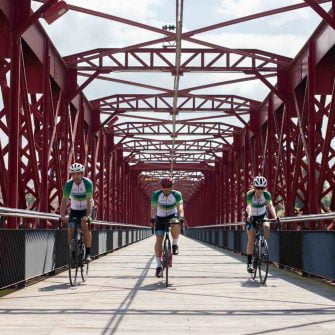 Cyclists crossing a red bridge in Catalonia, Terres de l'ebre region