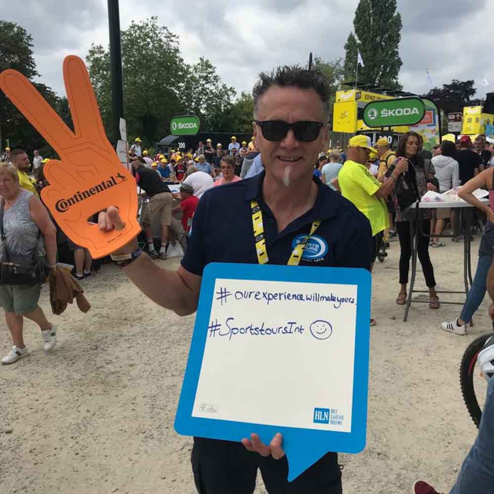 An operator is standing with a signboard in his hand of Tour de France tour packages