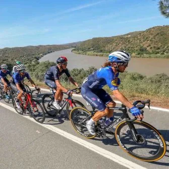 Some cyclists riding a bicycle by side river on Tour of Algarve