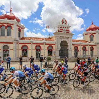 Cyclists riding bicycles through the front of the shrine on the Tour of Algarve