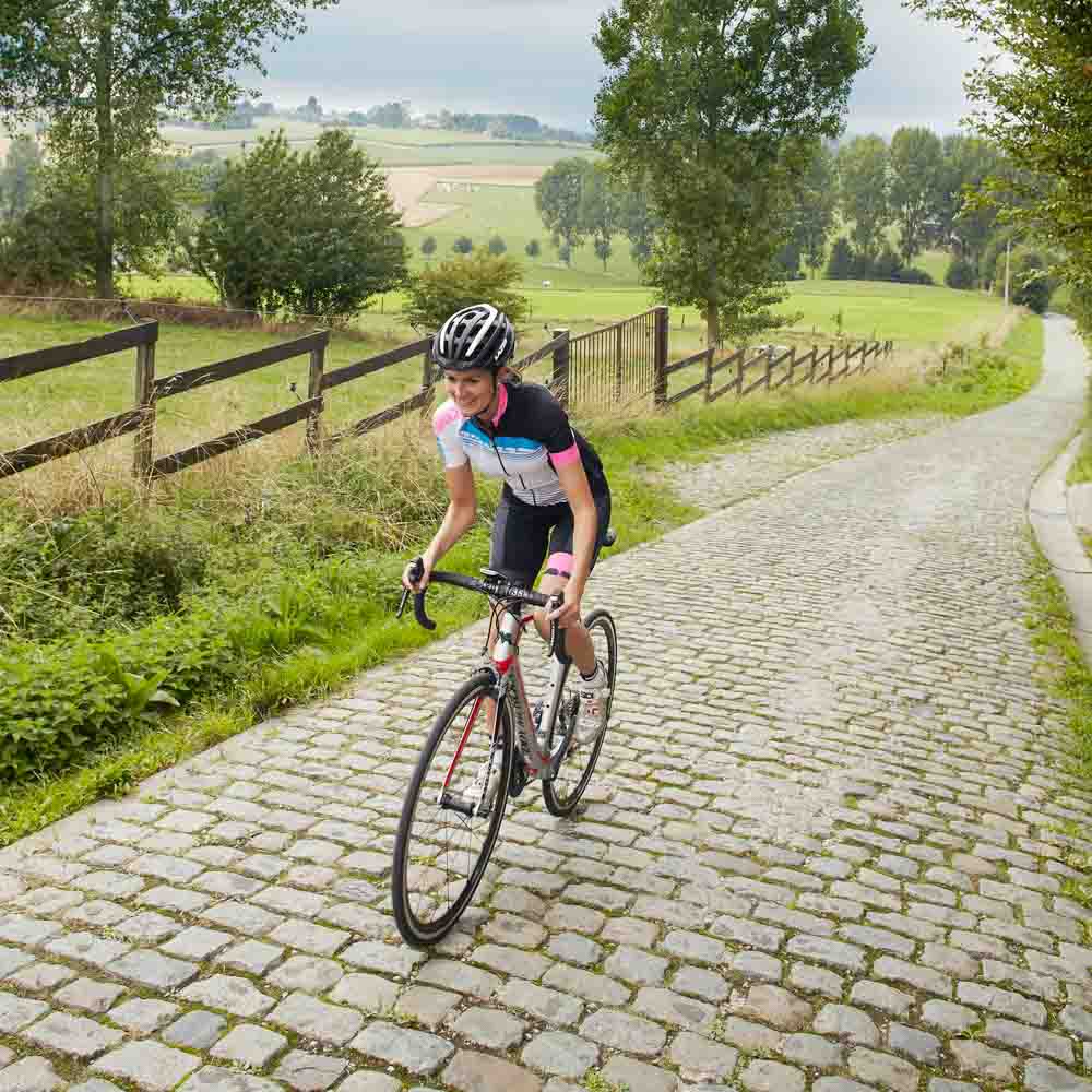 A girl cyclist rides a bicycle on a brick road bike tours belgium