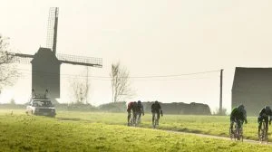 Cyclists on a Belgium cycling holiday with windmill backdrop
