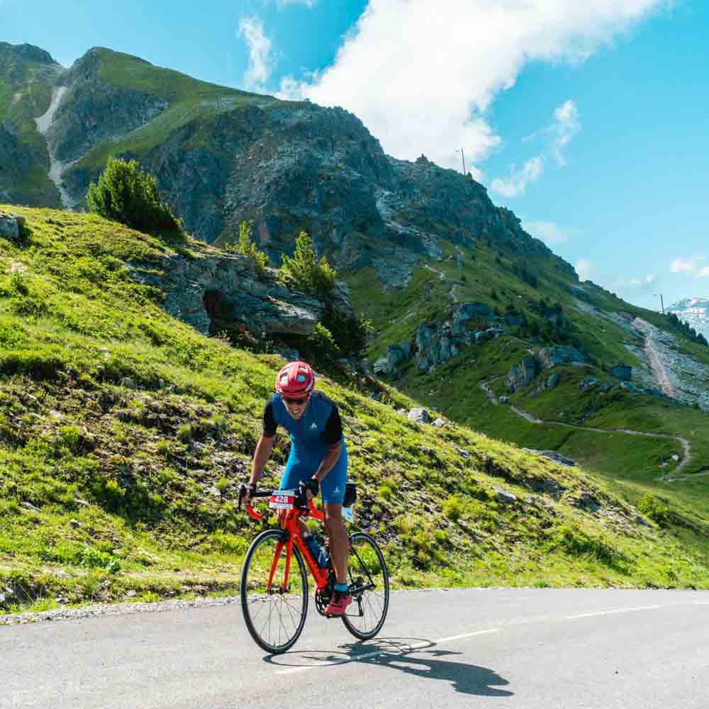 A cyclist cycling a red cycle in the alps mountain sloping road