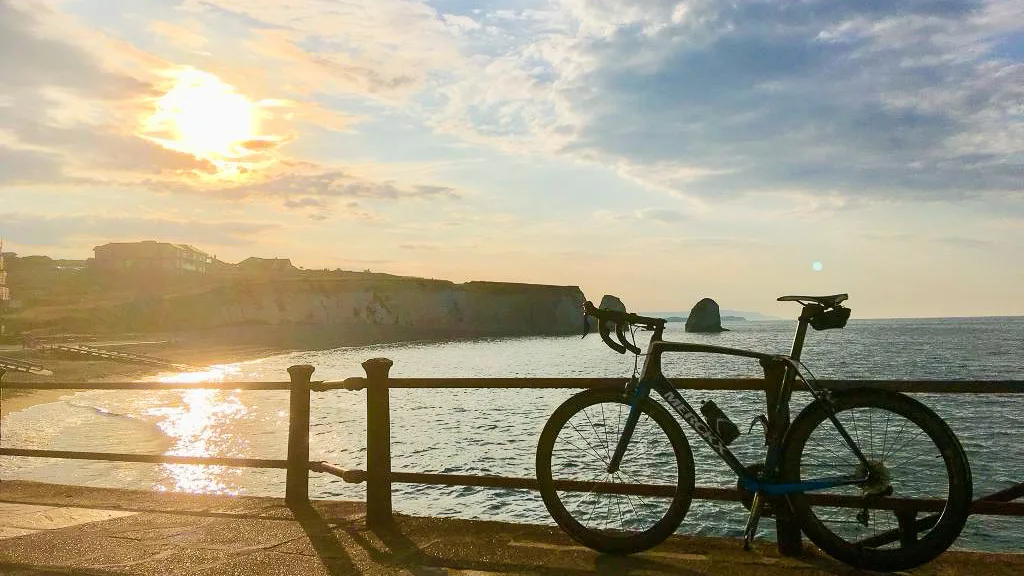 A road bike propped up against a railing overlooking the sea at sunset on the isle of wight