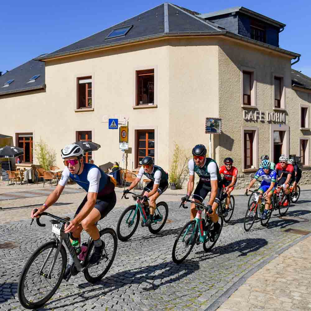 Cyclists ride their bicycles in front of Cafe dohm in the city gran fondo Luxembourg