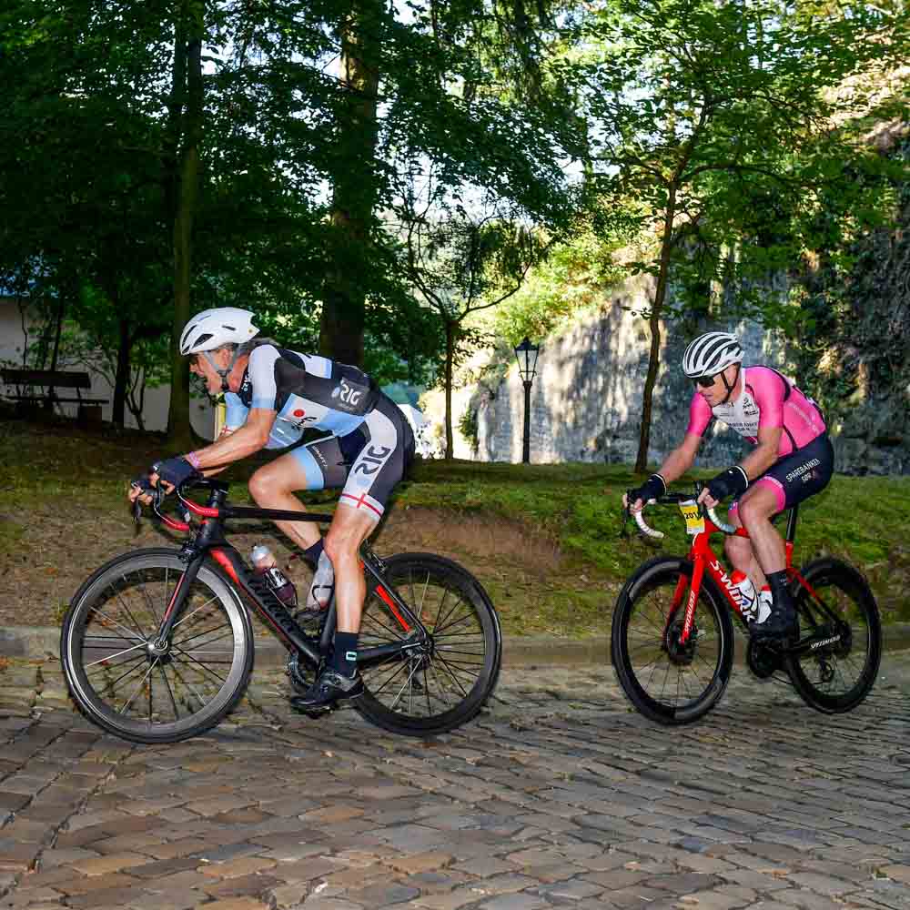 Two cyclists ride bicycles on a rocky mountain road in the city gran fondo Luxembourg