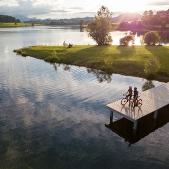 Two cyclists are standing by the lake on the German Alps cycling holidays