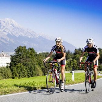 The two cyclists are cycling on the Austrian Alps cycling holidays on the road