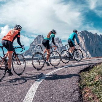Three cyclists ride a mountain slope in the Italian Alps cycling holidays