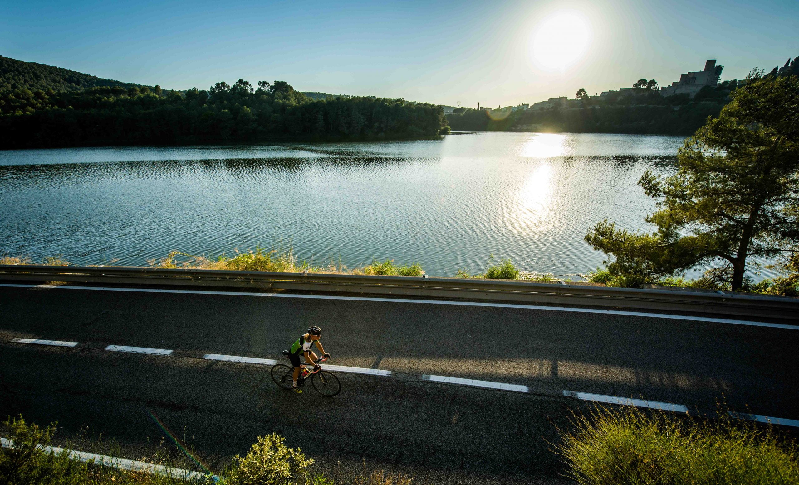 Cyclist cycling past a lake in Penedes region