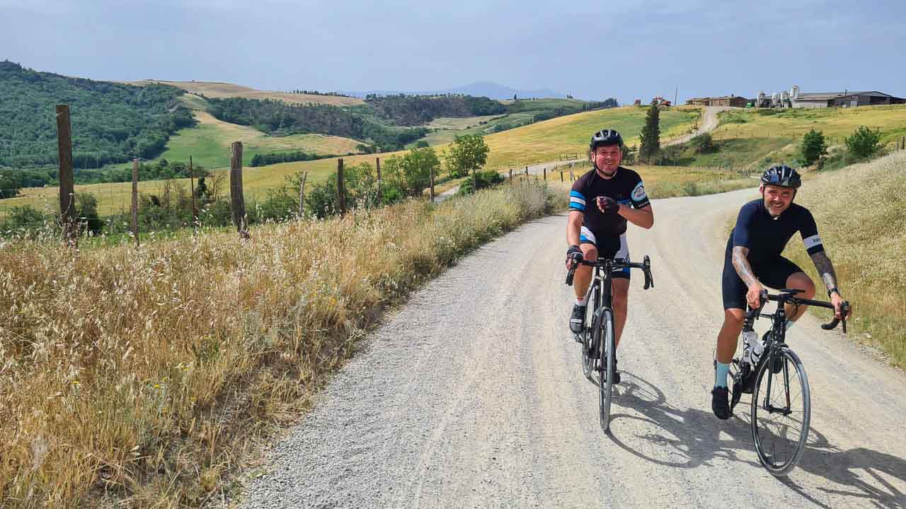Two cyclists cycling on Strada Bianche in Tuscany near Pienza