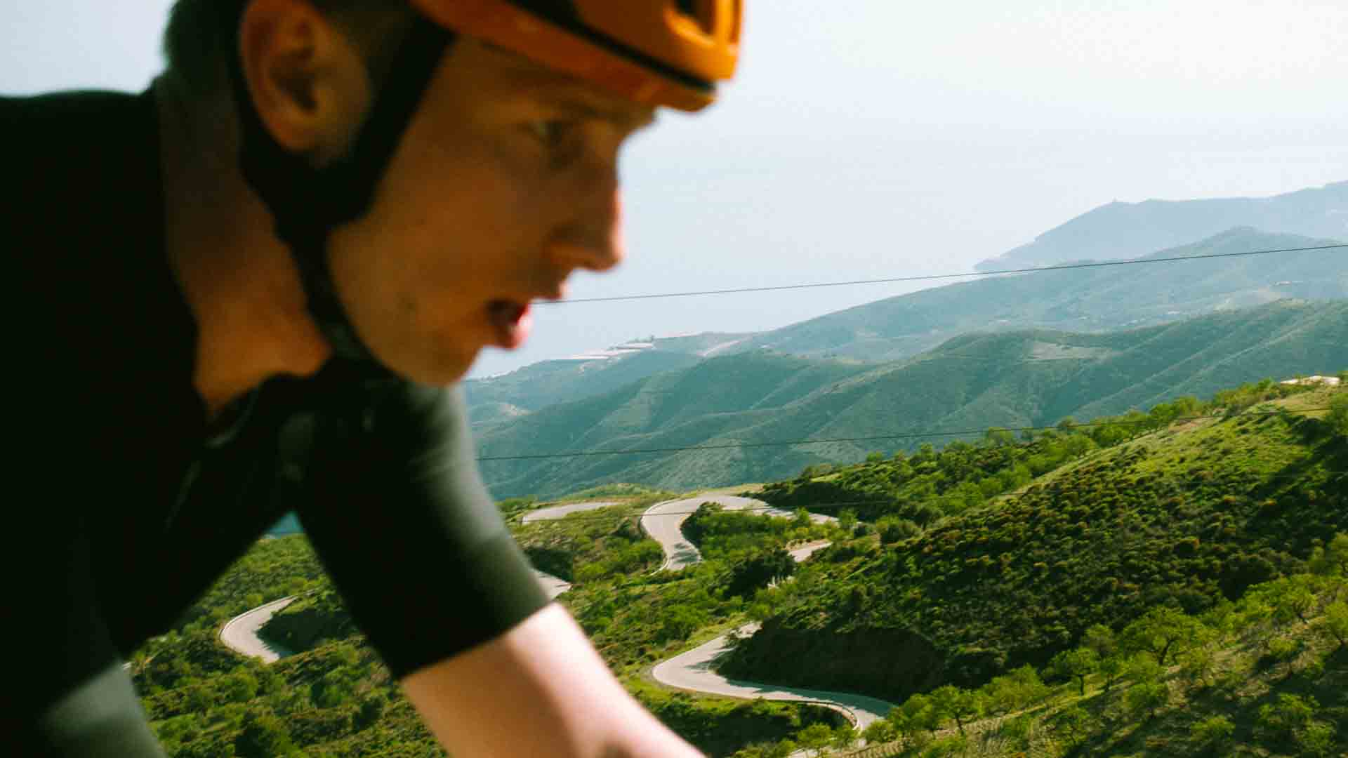 Male cyclist with switchbacks on mountain road