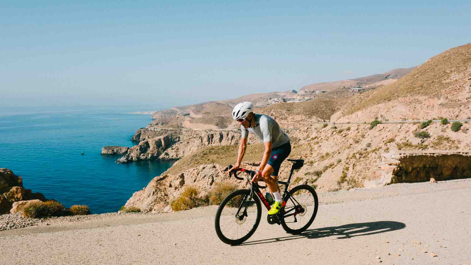 Cyclist with sea and cliffs behind
