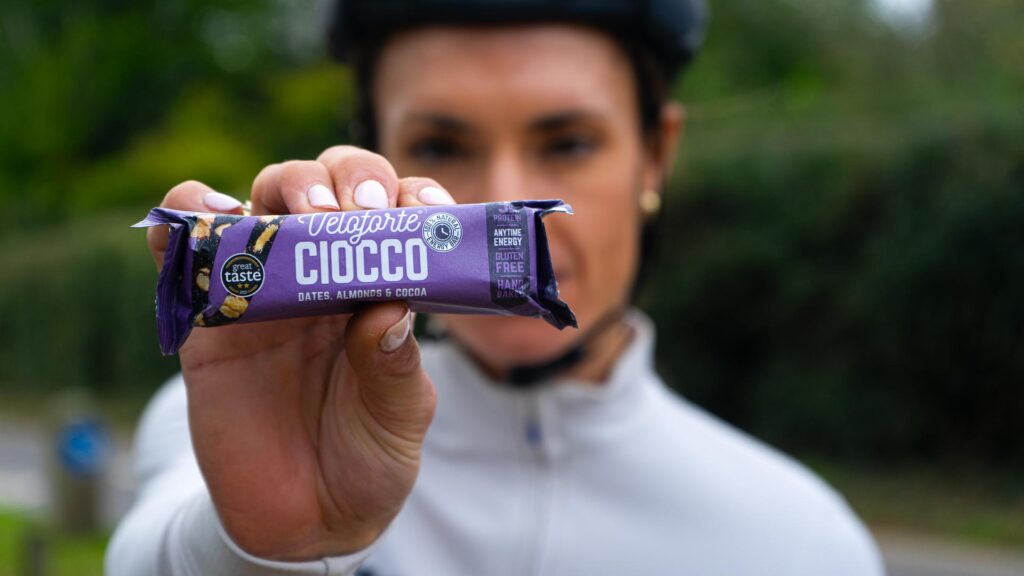 Cyclist holding a Veloforte Ciocco energy bar in purple wrapper