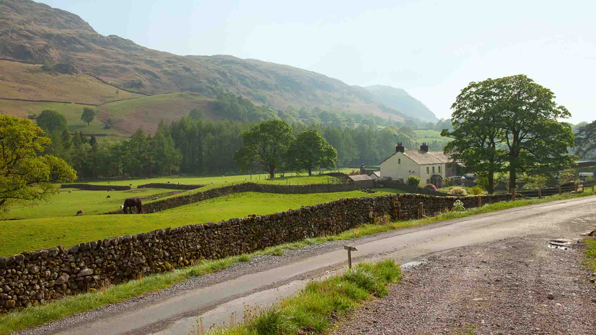 View to white farm building surrounded by countryside in Lake District