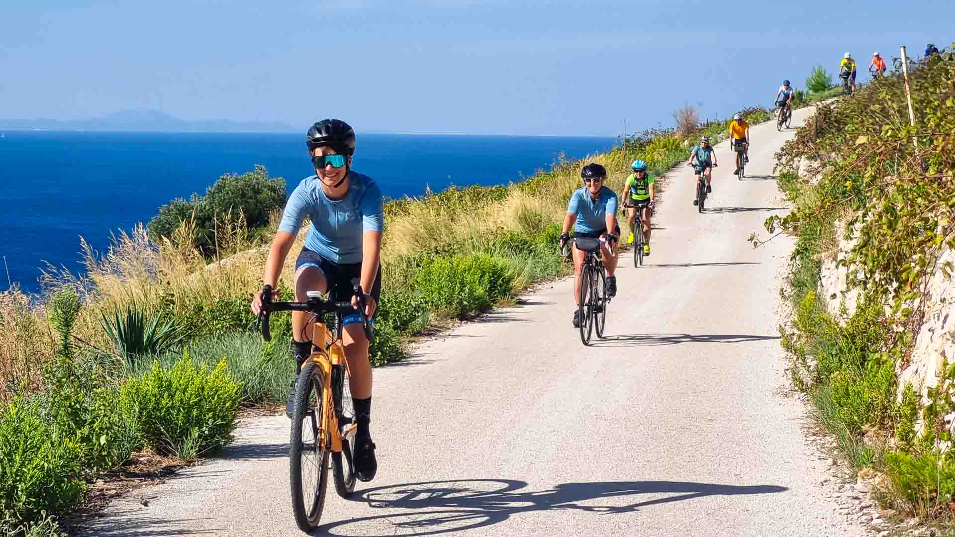 Line of cyclists cycling on gravel roads by the sea in Dalmatia Croatia