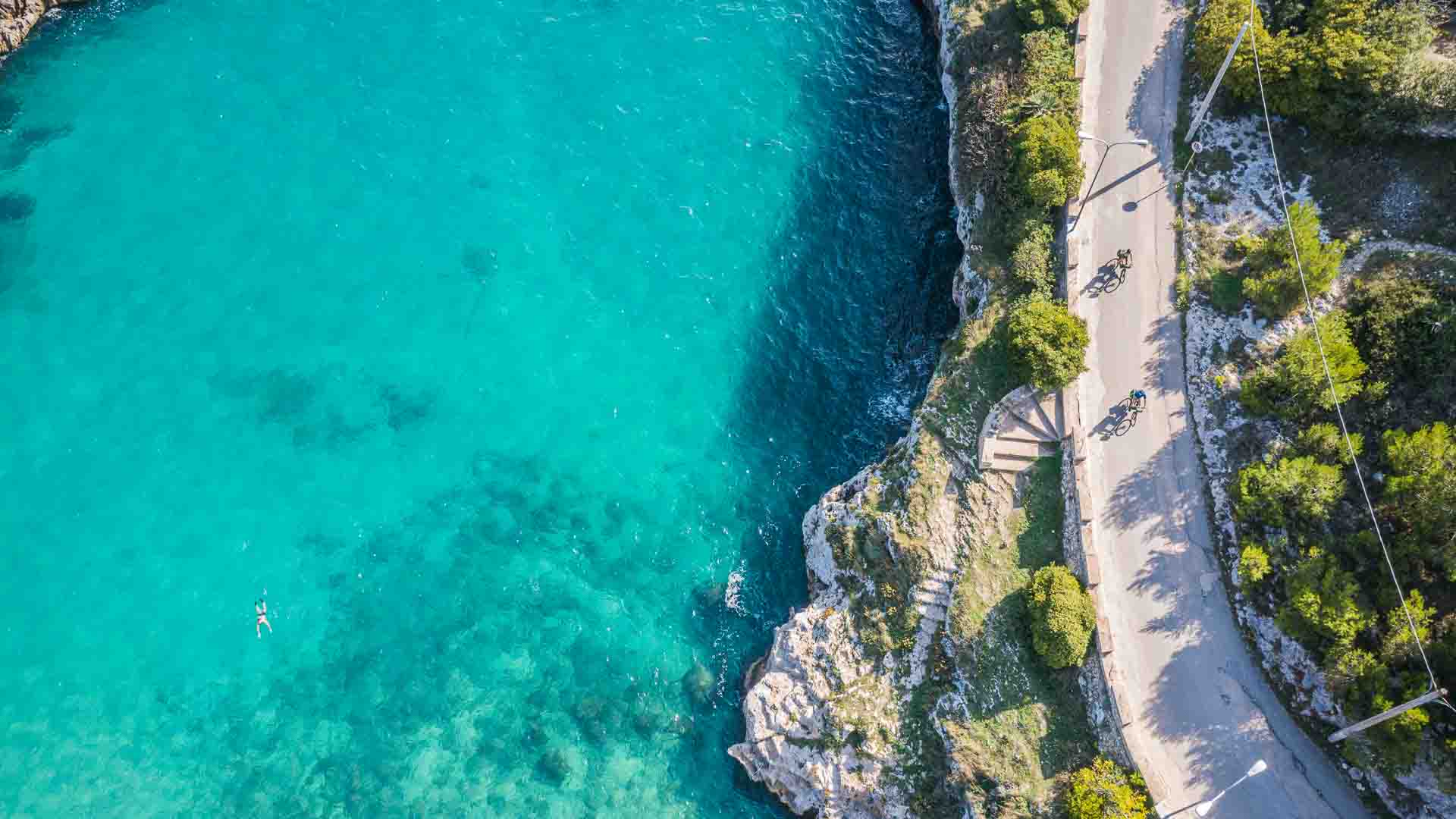 Aerial view of road alongside turquoise sea in Italy