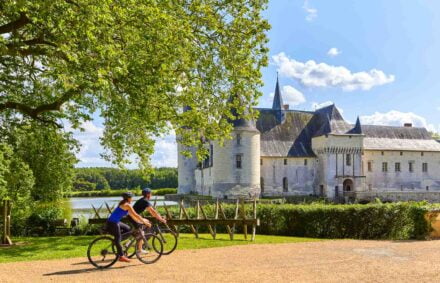 Two road cyclists enjoy the castle Plessis Bourre in the Loire valley near Angers