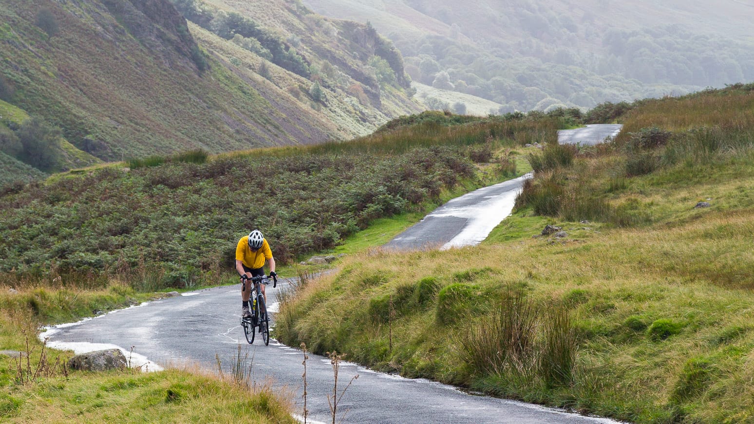 Cyclist on steep hairpin bends on Handknott pass in English Lake District 
