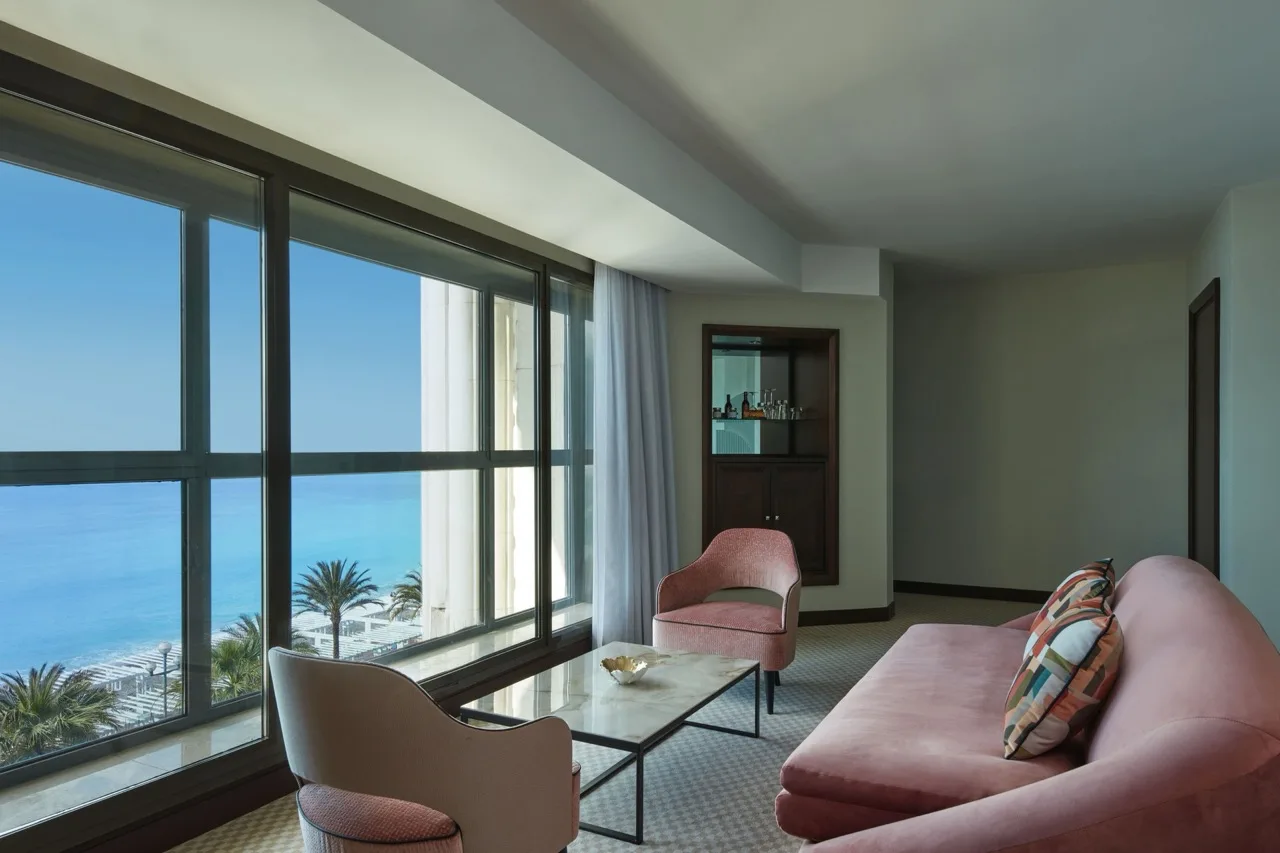 Resting area at Hyatt Regency Nice Palais de la Méditerranée with pink sofas, accent table, and glass walls overlooking the sea