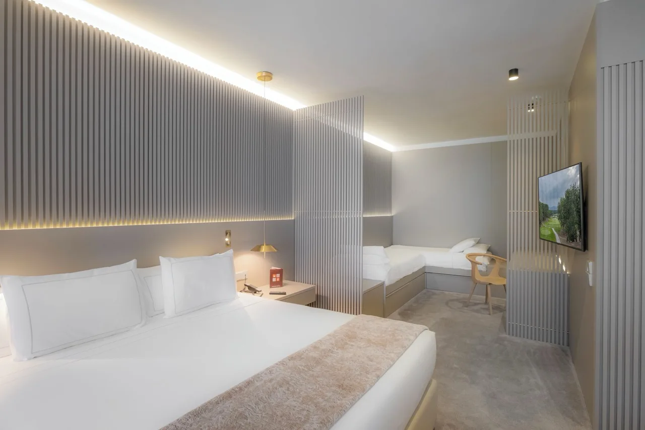 Modern-style bedroom at Carlemany Girona with a glimpse of the L-shaped sofa in the connected living room