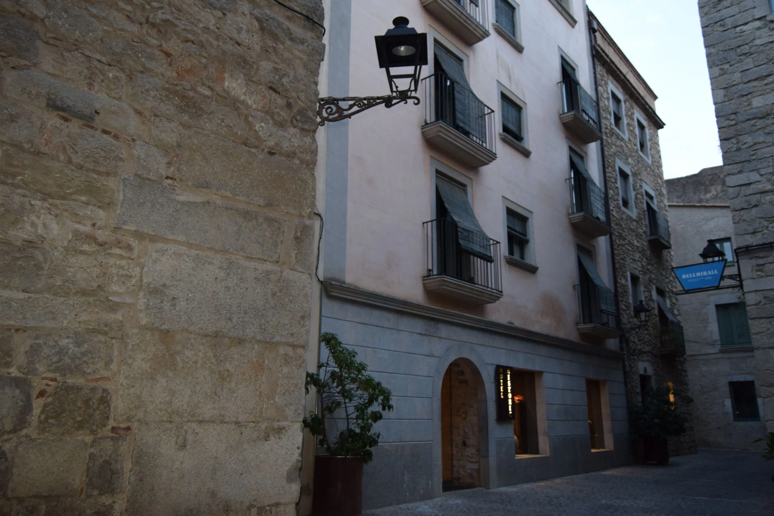 Exterior of Hotel Històric in Girona, featuring rustic stone walls and balconies in the old town area