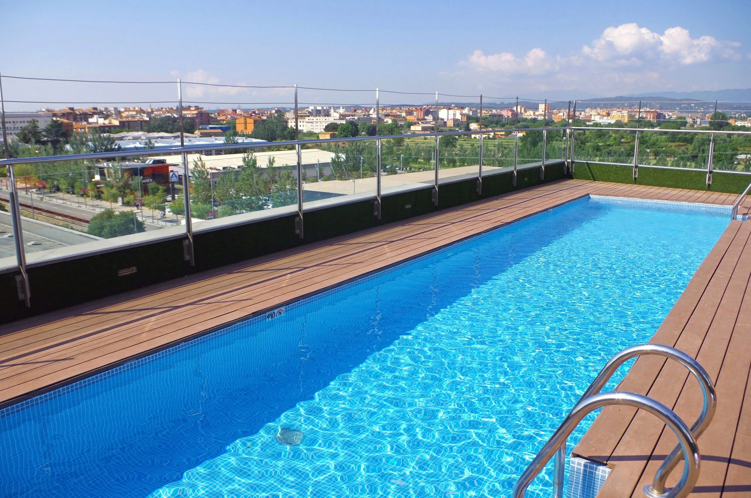 "Rooftop lap pool at DoubleTree by Hilton Girona with views of surrounding greenery and nearby buildings