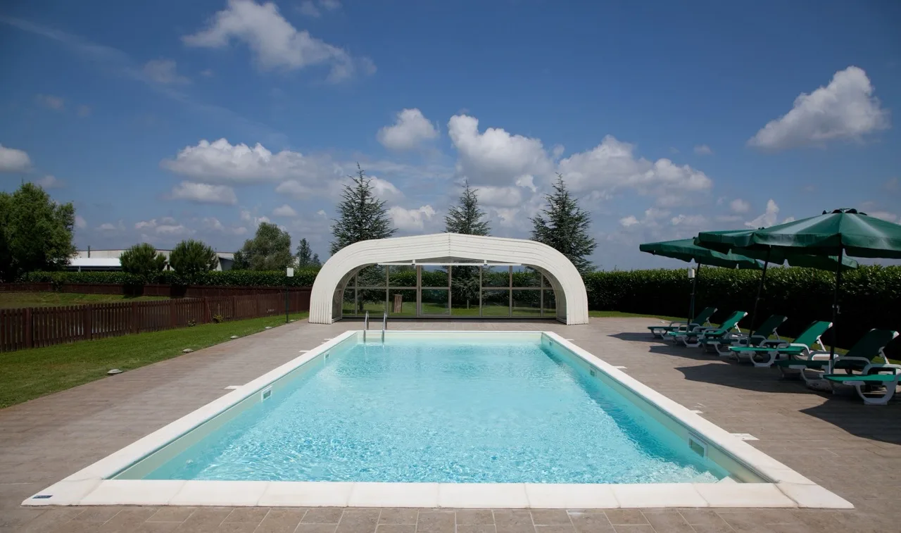Outdoor pool at Lo Scoiattolo Piedmont Bike Hotel in Pralormo with sun loungers and umbrellas on the right side