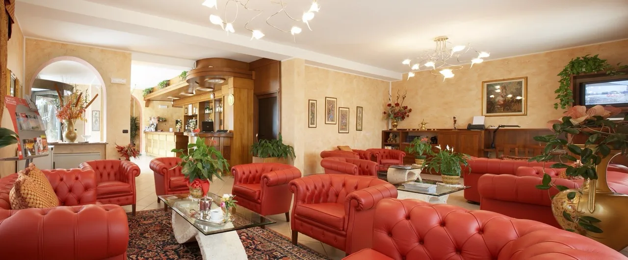 Lobby at Lo Scoiattolo Piedmont Bike Hotel with orange-red sofas and accent chairs in a classic interior