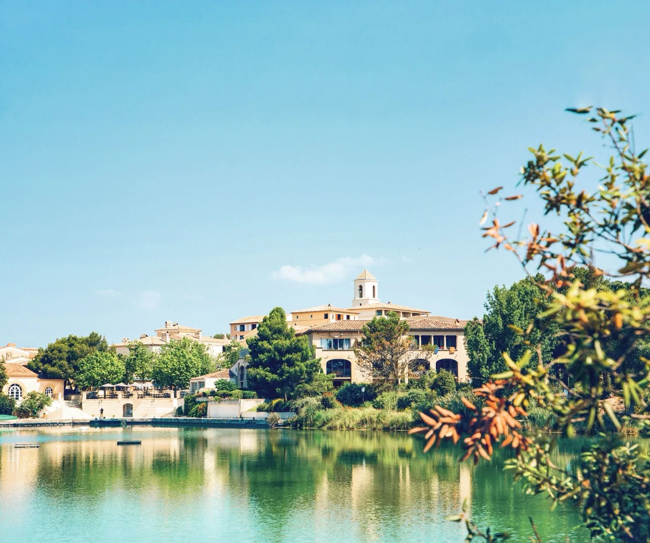 Distant view of Village Pierre & Vacances Pont Royal en Provence in Mallemort with river in front and surrounded by trees