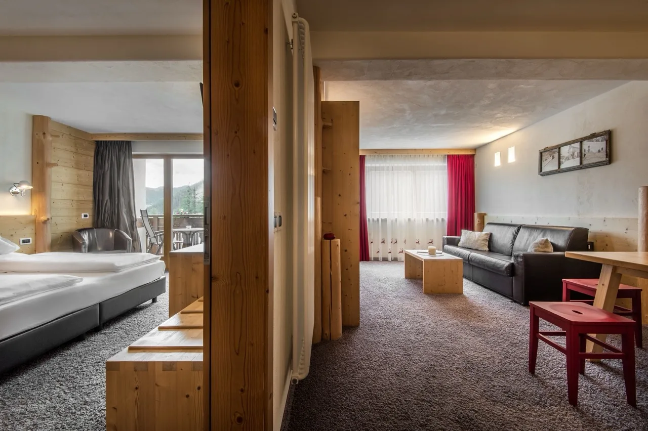 Suite at Hotel Gran Ciasa in Colfosco with bedroom and living room separated by wooden divider